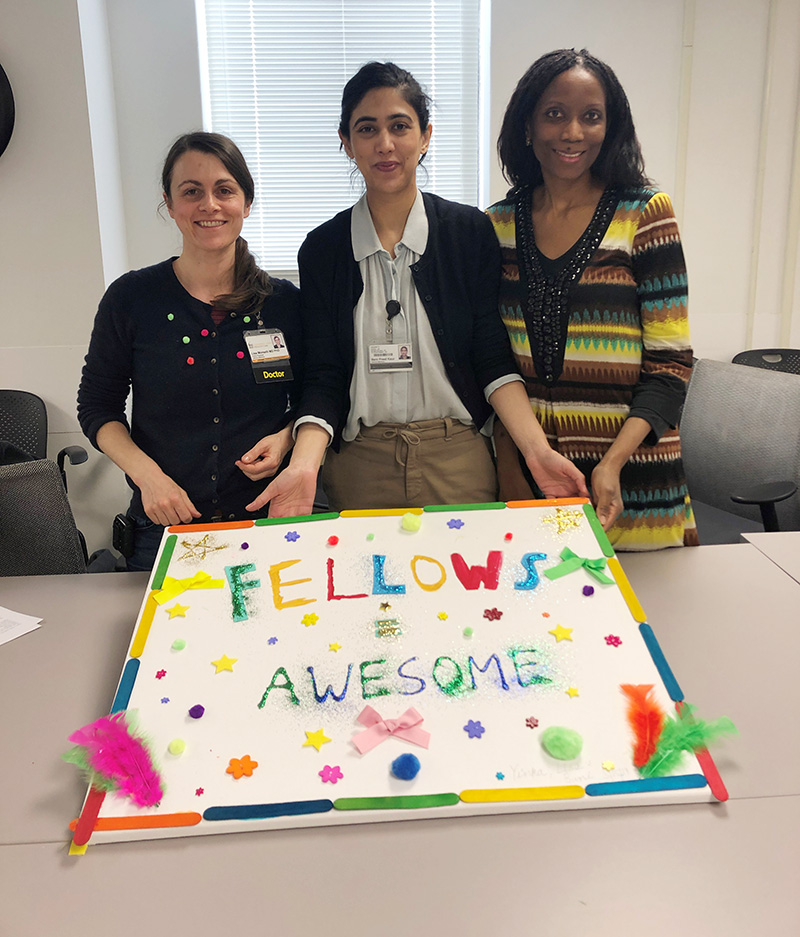 three fellows posing with a colorful sign reading "Fellows Awesome"